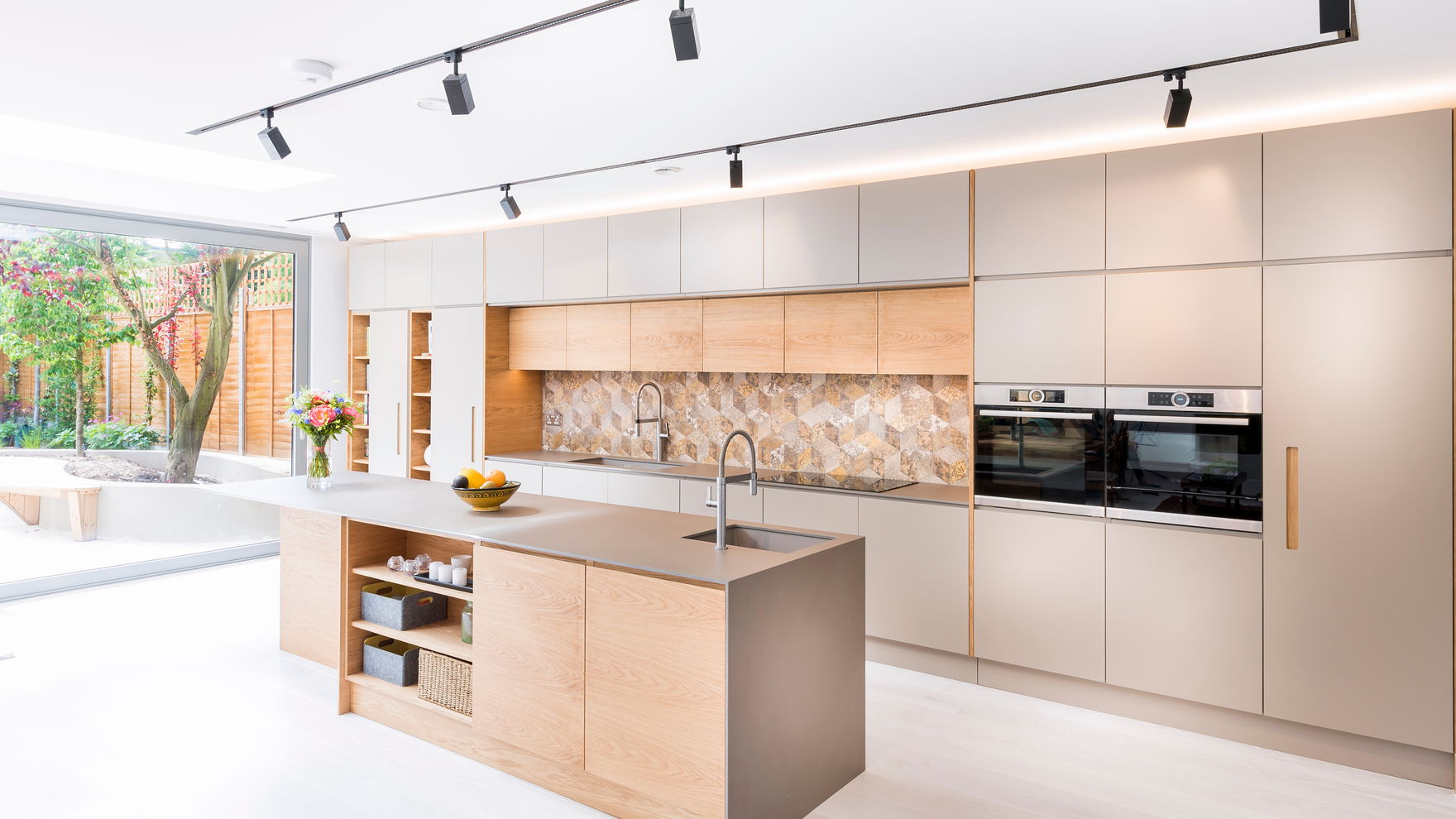 A bright modern kitchen with black track lighting along the ceiling and a timber-fronted island